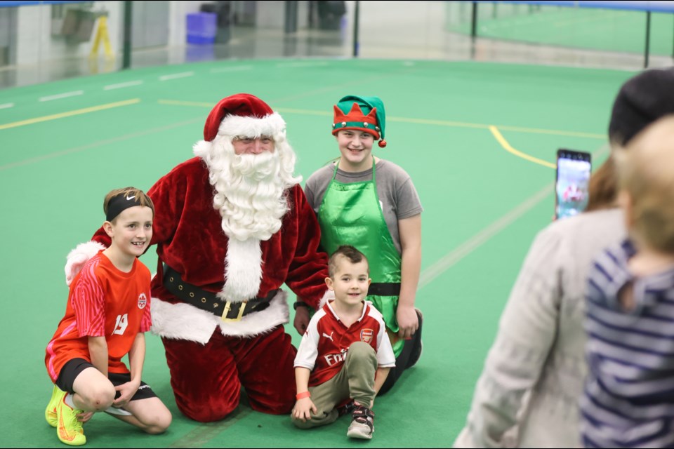 Soccer fans Jaxon Schneider (left) and brother Lucas get a photo with Santa Claus and his elf during the Soccer with Santa event at the Cavalry FC Fieldhouse on Dec. 10.