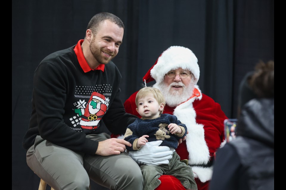 Tyler Hollick and his son Brooks get a photo taken with Santa Claus during the Dawgs Holiday Hoopla at Duvernay Fieldhouse on Dec. 10.