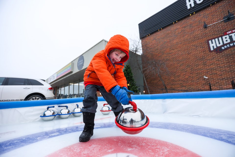 Odin Gulbrandsen throws a rock on the miniature curling rink constructed by Hub Town Brewing Co. on Jan. 15.