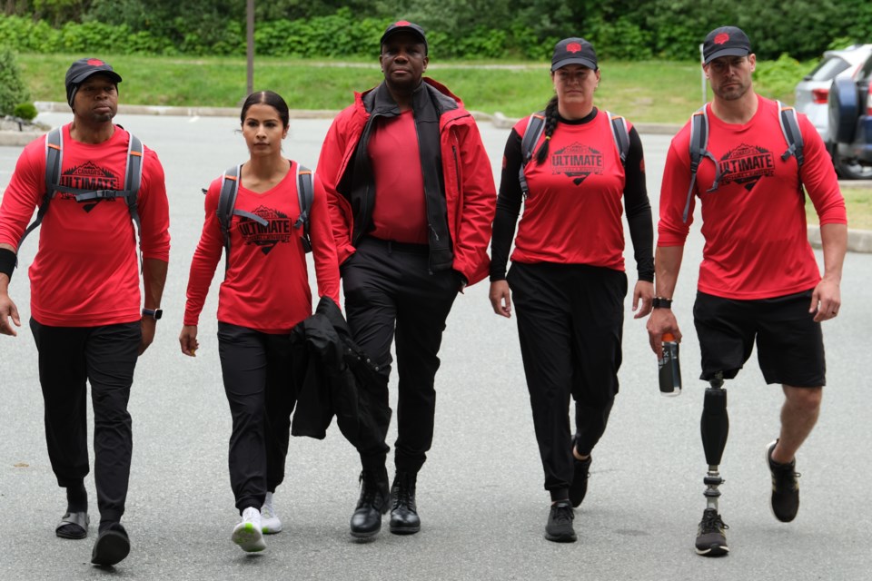 Okotokian Chris Cederstrand, right, walks with his Canada's Ultimate Challenge teammates and coach and Olympic sprinter Donovan Bailey (centre). 