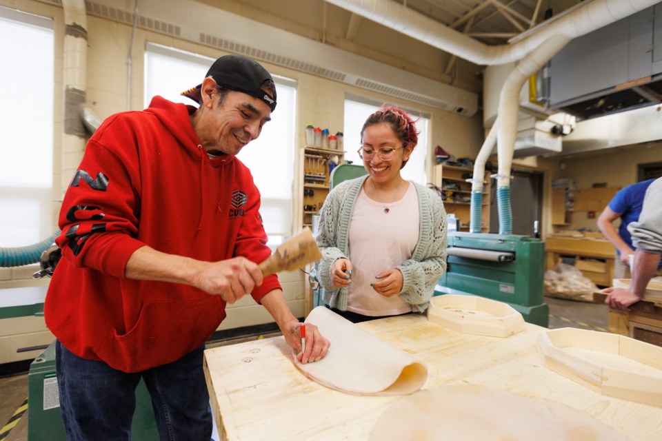 Siksika-based Blackfoot educator Clinton Turningrobe helps student Amelia Sanchez-Bucio punch holes through cow hide in a lesson on traditional Blackfoot drum making at Holy Trinity Academy on March 3, 2023.