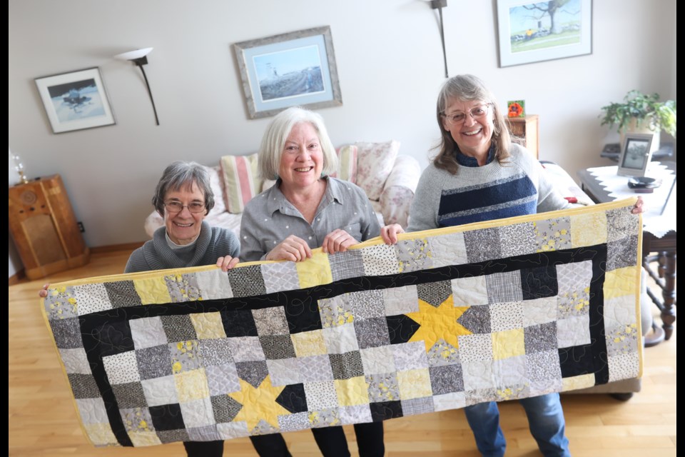 (Left to right) Victoria's Quilts members Jacquie Rhodes, Debra Graham and Joanne James pose with a quilt on March 11, 2023. Victoria's Quilts is a national volunteer organization that makes quilts for cancer patients.
