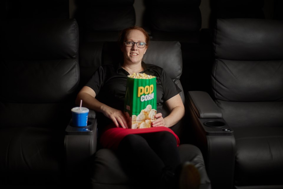 Okotoks Cinemas general manager Amber Wigg lounges in one of the theatre's new VIP recliners on March 22, 2023. The new seating, along with upgraded standard seats, were purchased after a 2021 crowdfunding campaign.