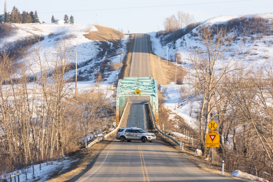 A police cruiser blocks the Highway 552 bridge over the Highwood River on March 30, 2023 as the RCMP conduct a criminal investigation in the area. The road reopened later Friday afternoon.