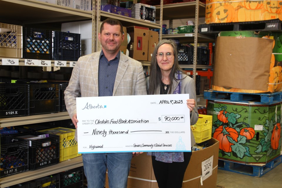 Highwood MLA RJ Sigurdson presents a cheque for $90,000 to Okotoks Food Bank director Pamela McLean in the organization's warehouse on April 4. The donation was made possible through Alberta's Donation Matching Grant and Food Bank Grant. 