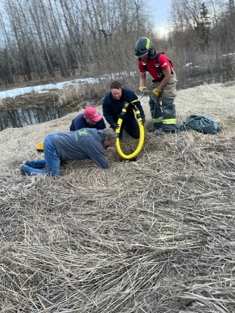 Firefighters and others work to rescue a man from an old septic tank on April 16, west of Dawg's Stadium and south of 370 Ave on the boundary between Okotoks and Foothills County.