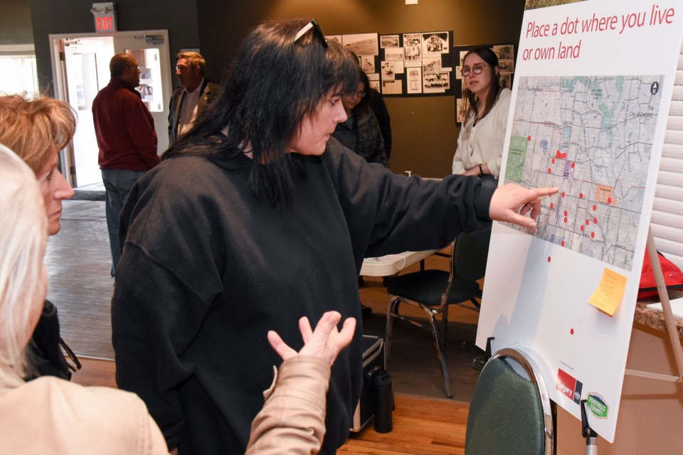 Taryn Ferguson, centre, a resident of Foothills County, points to a map marking land proposed for annexation into Calgary during an open house about the proposal at the DeWinton Community Hall on April 27.