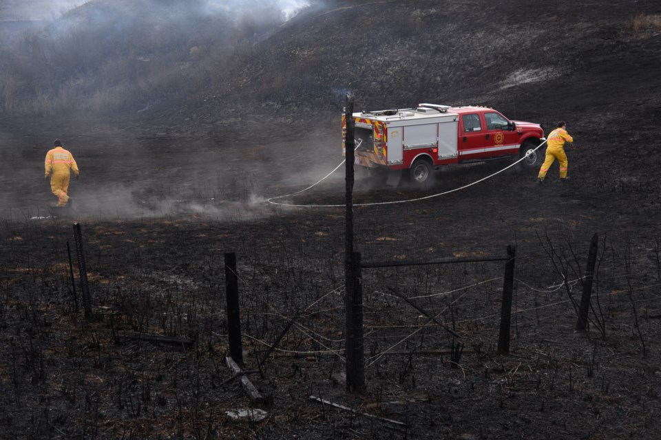 Crews work to put out the remnants of a grassfire in Diamond Valley on April 25.