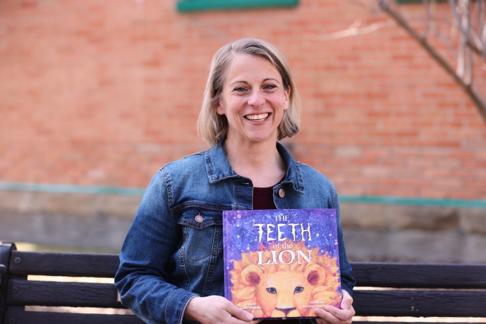 Okotoks artist Jennifer Stables holds out the children's book she illustrated, The Teeth of the Lion, written by Barry Thorson, on April 28. The book was produced by Calgary Reads for disadvantaged children.