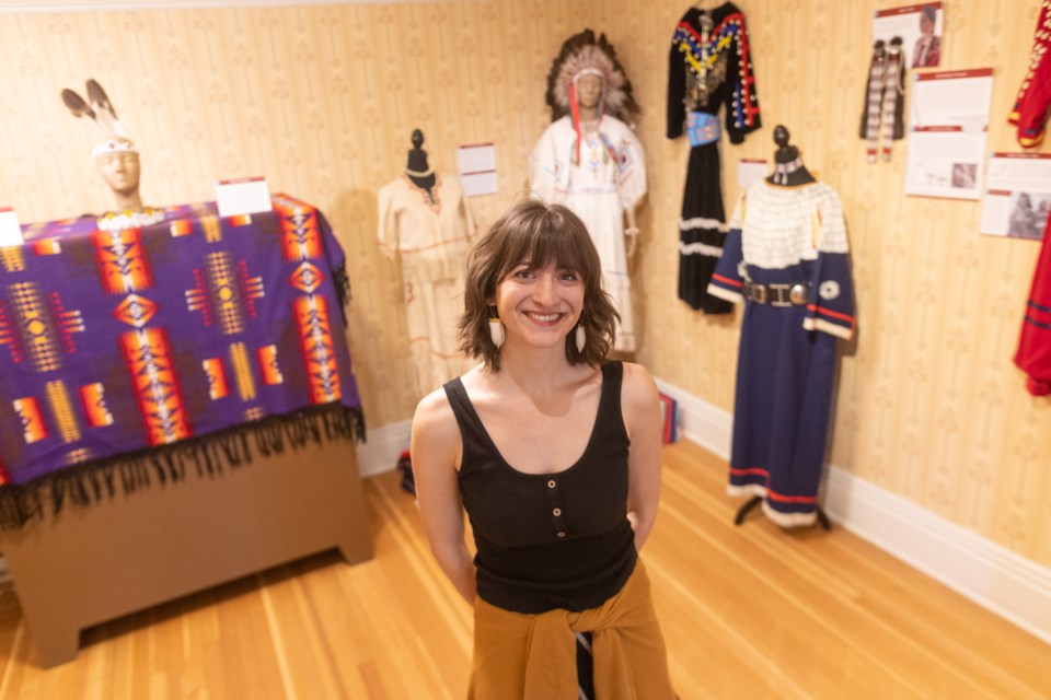 Alyssa Koski stands among her exhibit of traditional Blackfoot clothing at the Okotoks Museum and Archives on June 2. Coming from a Kainai background, Koski gathered most of the articles in the exhibit from family and are either original historic pieces or recreations by her grandmother Pauline Dempsey.