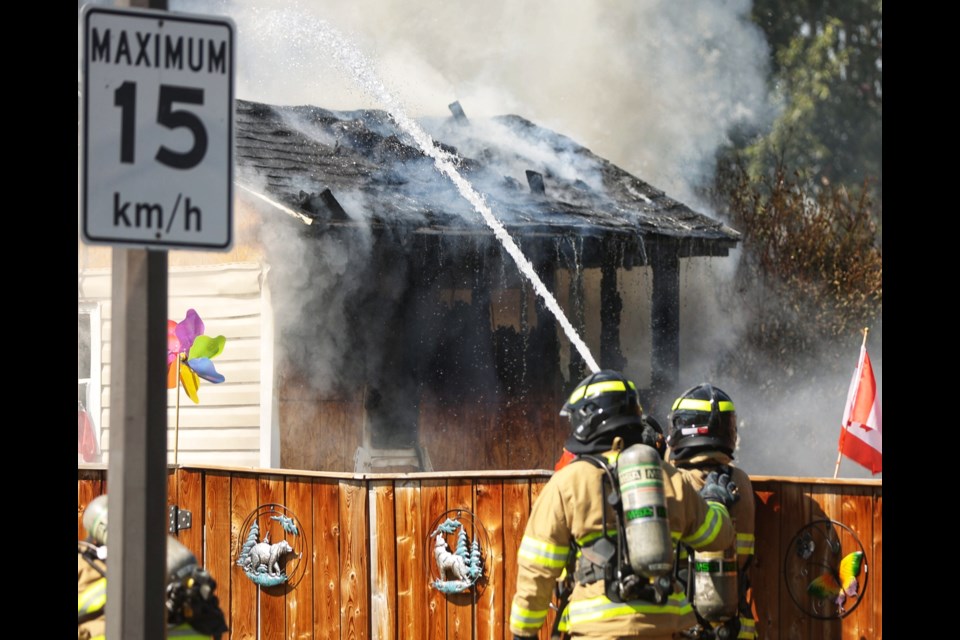 Firefighters battle a fire at a home in the Okotoks Village trailer park on July 29. The fire originated in a shed before spreading to the main residence.