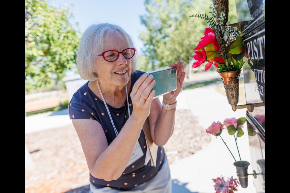 Wendy Schultz captures a digital image of a memorial plaque on a columbarium at the Okotoks Cemetery on Aug. 11.