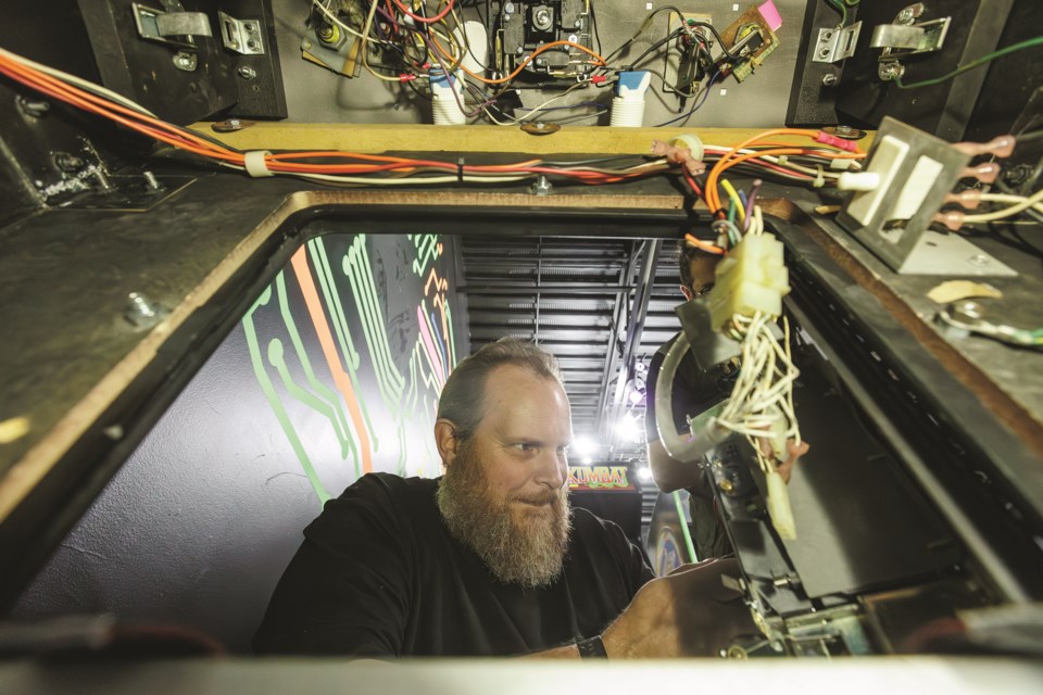 Retro Oasis owner Steve Smith works on the coin mechanism for the Capcom arcade game '1942' on July 26.