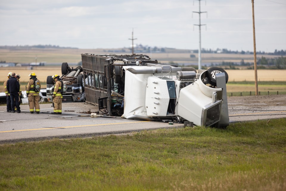 Emergency crews attend the scene of a semi car hauler rolled over on Aug. 24 which blocked the southbound lanes of Highway 2 just before 498 Avenue. The semi's cargo was strewn about the roadway as well.