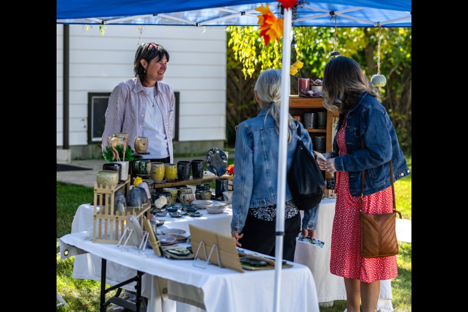 Dee Lueck shows her pottery wares to patrons during the Elma Street Arts Walk on Sept. 9.