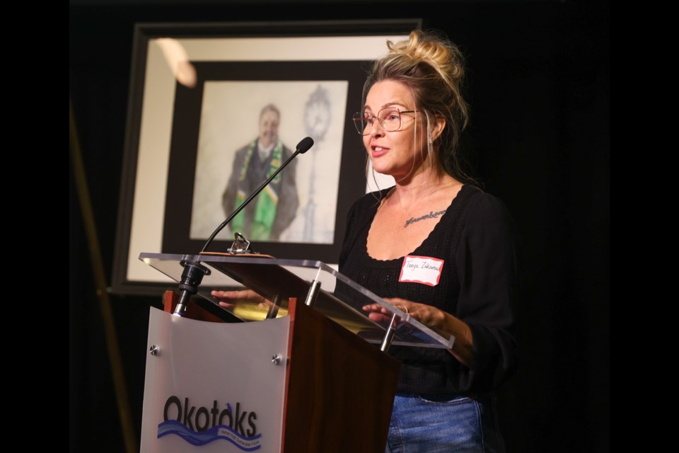 Okotoks's inaugural artist in residence Tanya Zakarow speaks after unveiling the portraits she painted of impactful community members, such as late Mayor Bill Robertson (background) at the Face to Face 2023 event at the Rotary Performing Arts Centre on Sept. 29.