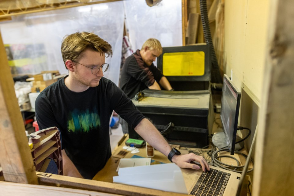 Ian Rose works at a computer controlling a laser engraver being worked on by brother Brendan in their workshop on Nov. 4, as part of their business Fantasy by Numbers. In 2020 the two struck out on the new venture, crafting wands, tabletop gaming accessories, and other fantasy items.