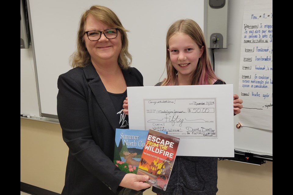 Author Dorothy Bentley presents Grade 6 student Madeleine Janzen with her prize for winning a student writing contest organized by the Foothills Writers Group. 