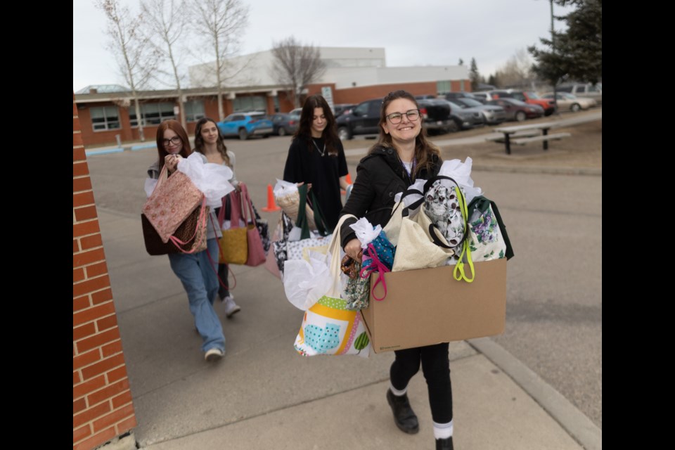 Students of Oilfields High School help Rowan House Emergency Shelter volunteer coordinator Beth Smith load up bags they sewed and filled with gifts for clients of the shelter on Dec. 1