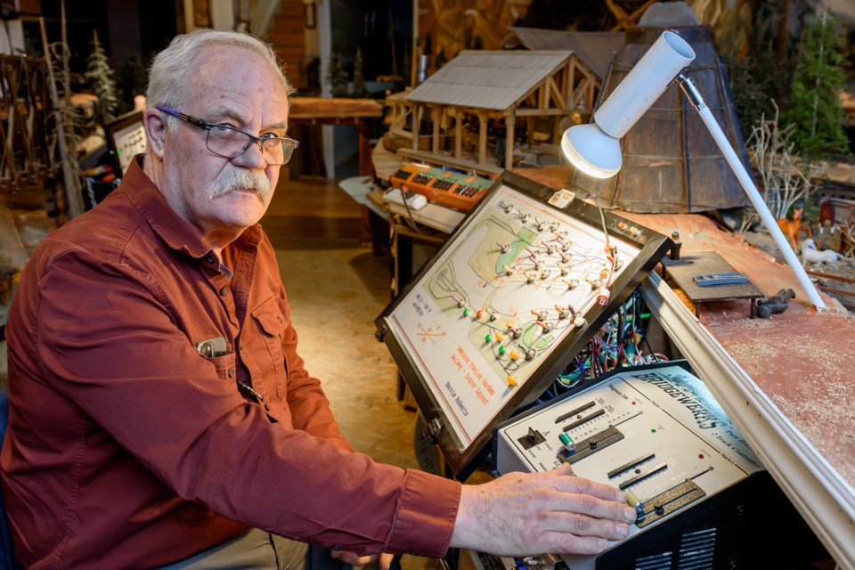 Barrie Roberts sits at the controls of a large model train layout in his DeWinton home on April 18.