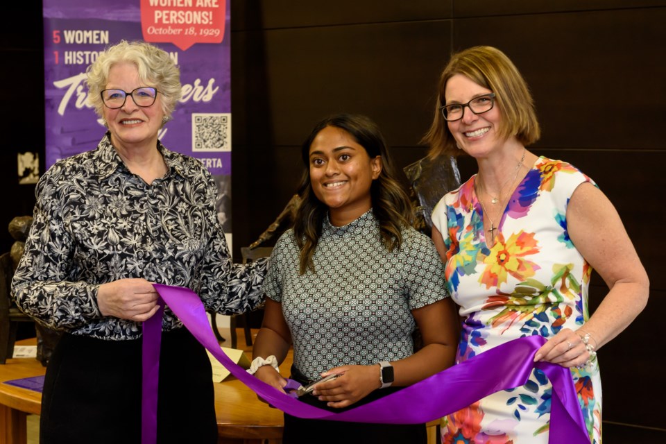 Famous 5 Foundation founder Frances Wright, left, Amlika Nair, centre, and Mayor Tanya Thorn, right, cut a ribbon to   launch the Famous 5 Foundation’s “Women Are Persons!” exhibit at the Okotoks Municipal Centre on March 7. The exhibit will be on display until March 28. 