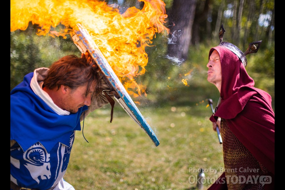 Knight Jason Carmody shields himself from a fire-breathing demonstration by Circus of Hell performer Doug Thompson during the Time Island historic reenactment festival at the Millarville Ag grounds on Sept. 15. (BRENT CALVER/Western Wheel)