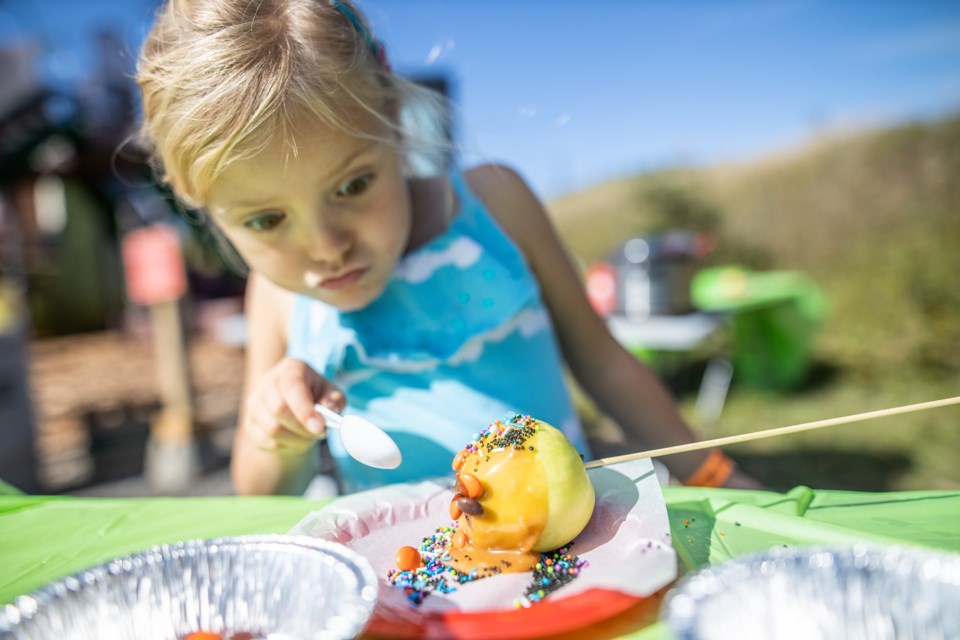 Edie Hands, 5, decorates a caramel apple at Apple Fest at Granary Road. This year's event takes place Sept. 26-27. (BRENT CALVER/Western Wheel)
