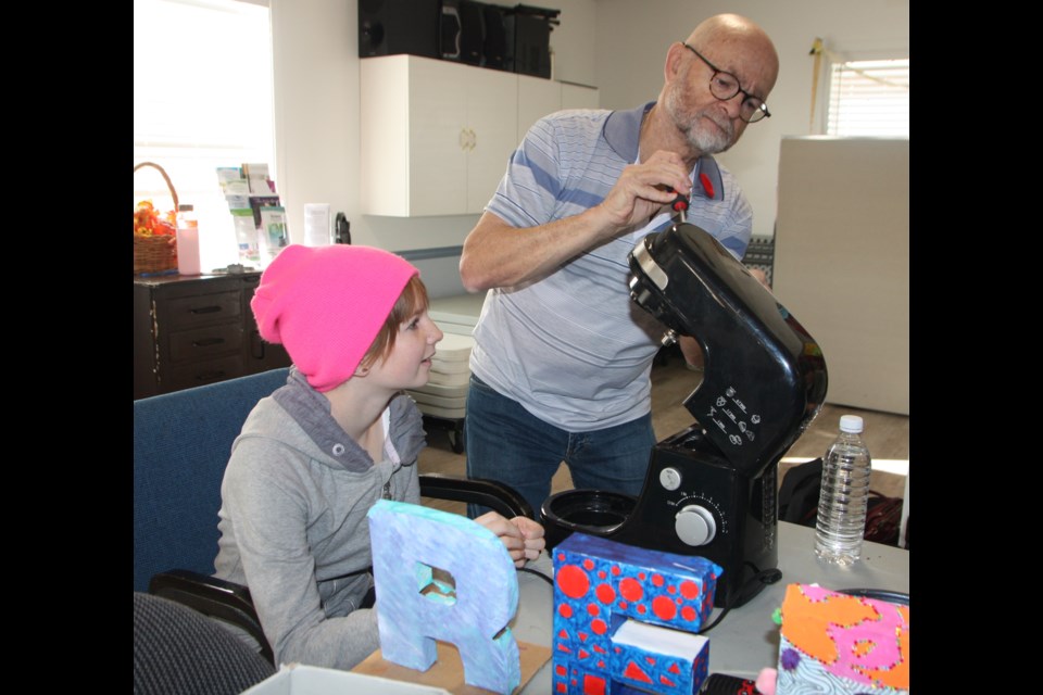 Ted Bain tinkers with a bread-maker while Ivy Gregoire, a Grade 8 student at OIlfields High School, looks on. The pair were participating at the Repair Café at the Griffiths Senior Centre in Black Diamond on Nov. 2. (Bruce Campbell, Western Wheel)