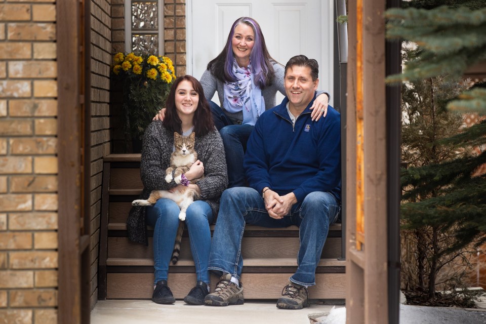 Dena and Jim Stewart pose for a socially distanced front porch portrait with their daughter Jaden and cat Petrie on March 28. During the COVID-19 pandemic, front porch portraits have taken off as a way for families staying at home together to document the unique if not difficult time. (Brent Calver/Western Wheel)      