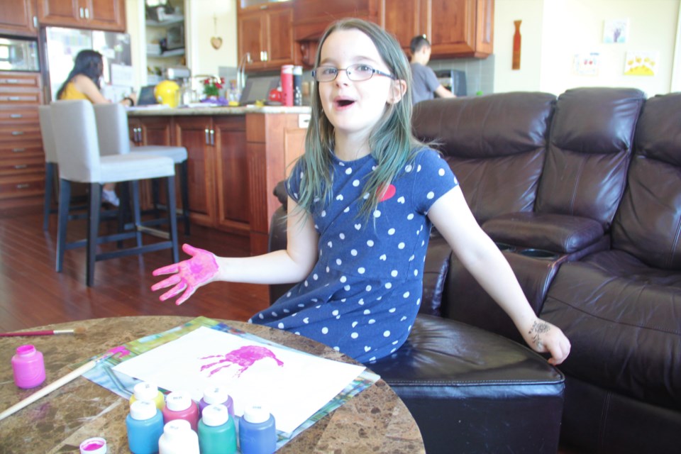 Hannah works on her handprint art on May 14.