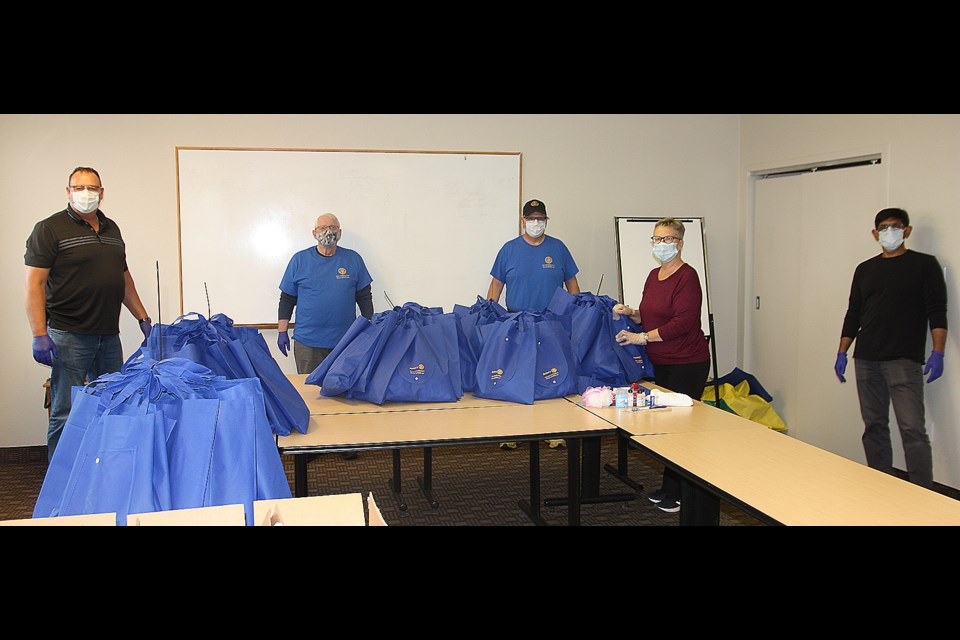 Okotoks Rotarians, from left, Robert Gollan, John Lockhart, Jeff Foss, Sharon Matson and Ash Khan stand behind the 100 Rotary care kits they packed for the Rowan House Emergency Shelter at Lakeview Inn and Suites on May 21. (Bruce Campbell, Western Wheel)