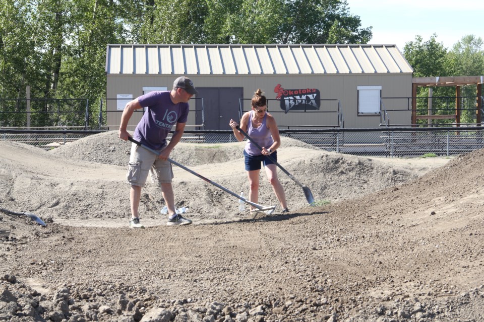 Laurie and Fabian Laforest rake the BMX track in Okotoks on May 30. (Krista Conrad/Western Wheel)