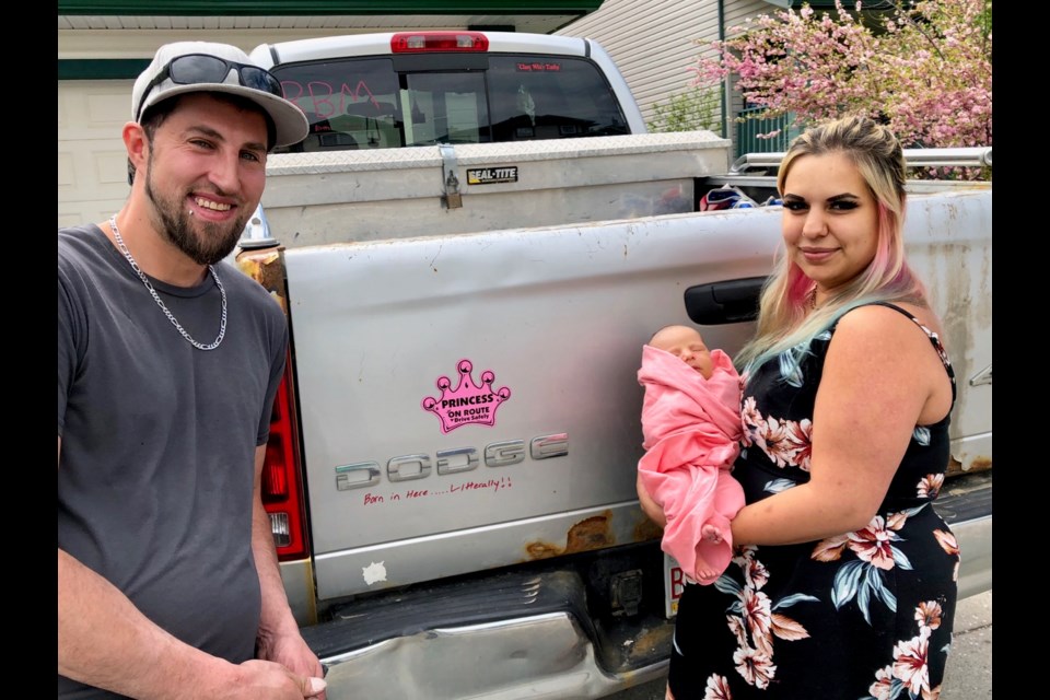 Cary Drews, left and Melissa Gordon with baby Svenja, beside the truck they were driving when she was born roadside May 27. (Photo courtesy Melissa Gordon)