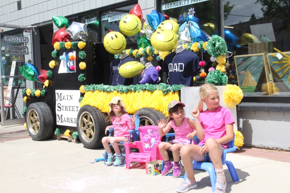 From left: Emma Adolph, Trisa Adolph and Natalia King, with Twin Timbers Rustic Design, hang out with the Main Street Market stationary float during the reverse parade in 2020. This year's event takes place June 19. (Krista Conrad/Western Wheel)