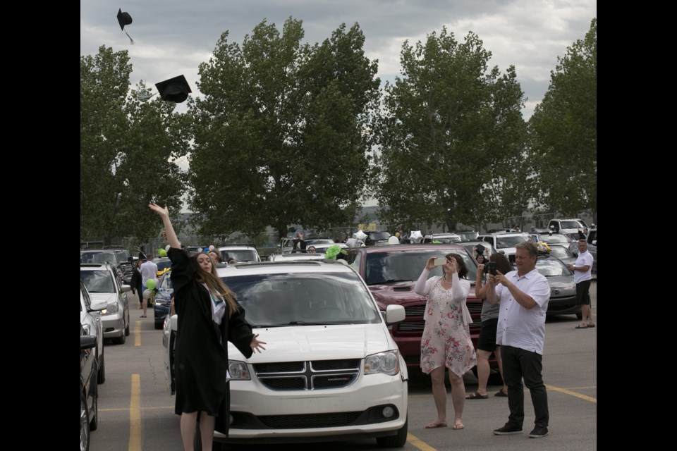 Parents snap photos as the Holy Trinity Academy Class of 2020 members throw their mortarboards at the outdoor graduation ceremony on June 26 at the Okotoks Recreaction Centre parking lot. The ceremony was outside to respect social distancing due to COVID-19. (Bruce Campbell, Western Wheel)