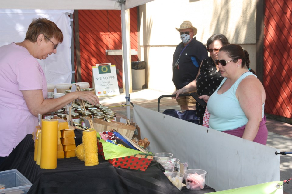 Gillian Osmars of Okotoks purchases some honey from Heather Inscho at the Forever Bee stand at the first Okotoks Elks Club's Farmers' Market on Elizabeth Street on July 4. (Bruce Campbell/Western Wheel). 