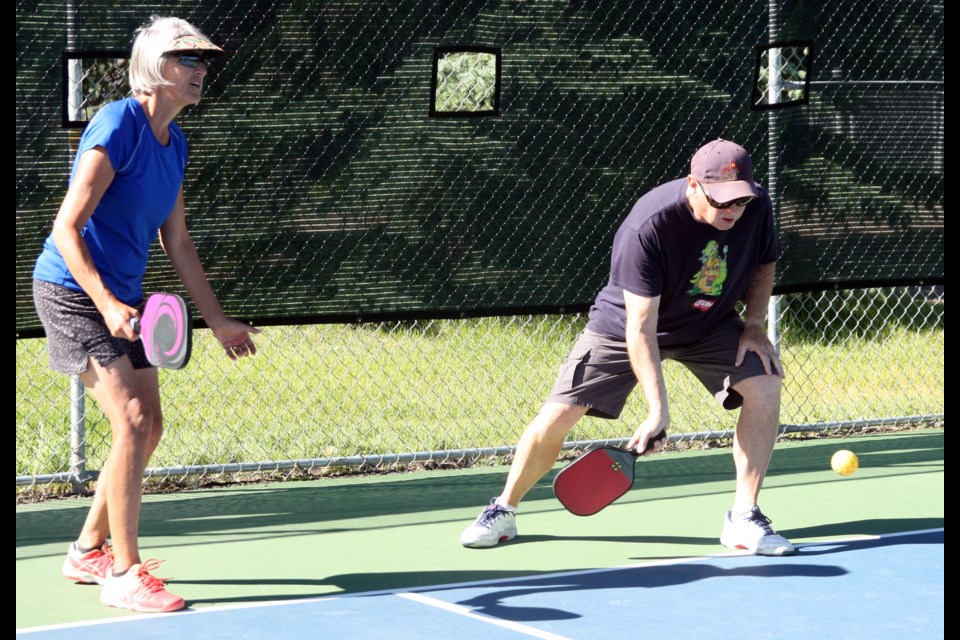 Jerry Bennett goes low during pickleball play on July 25 while his wife, Lori, gets ready for the return. The former Wilson Park tennis courts were converted to six pickleball courts this season. (Bruce Campbell, Western Wheel) 