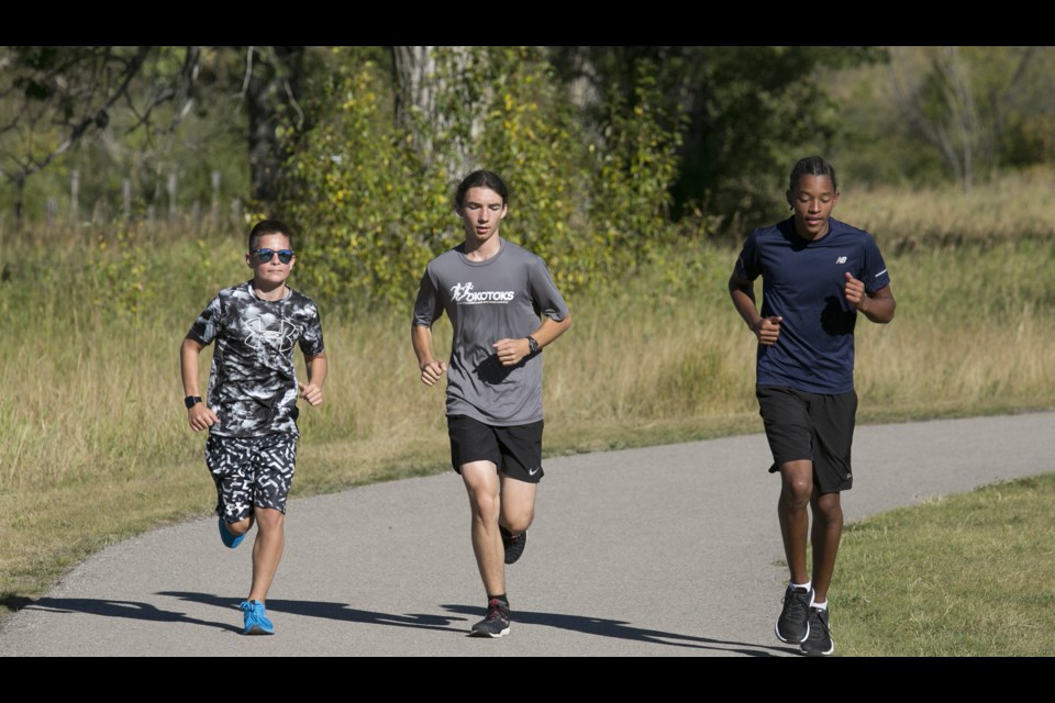 Okotoks Track and Cross-country club members Alec Finlayson, Hugh McGregor and Leon Spatz warm up before the 3.9km team run on Sept. 10 at the Mountainview pond path. (Bruce Campbell, Western Wheel)
