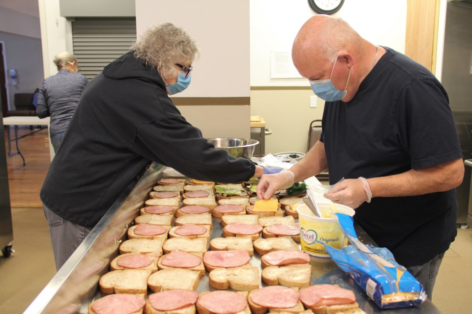 Mary-Ann Bowerman, left, and Bill Hutchison build sandwiches for bagged lunches at the Okotoks United Church on Oct. 26. The lunch program provides students in need with a healthy lunch made by volunteers. (Krista Conrad/Western Wheel)