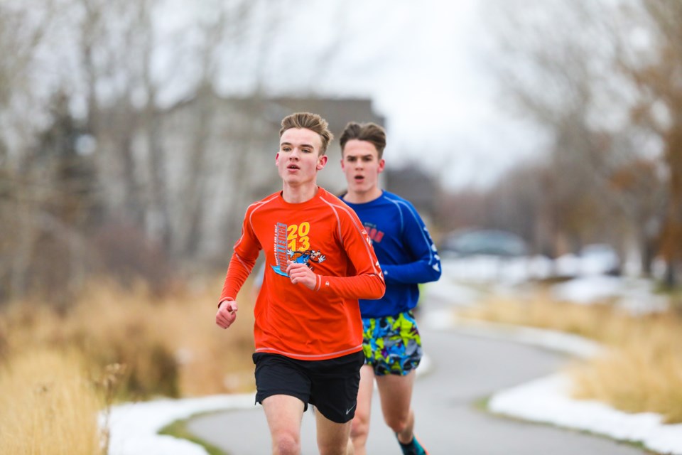 From left, cross-country runners Jacob and Josh Heuver take to the pathways near École Beausoleil on Oct. 29 in the final race of the Okotoks Track and Cross-Country mini race series. (Brent Calver/Western Wheel)
