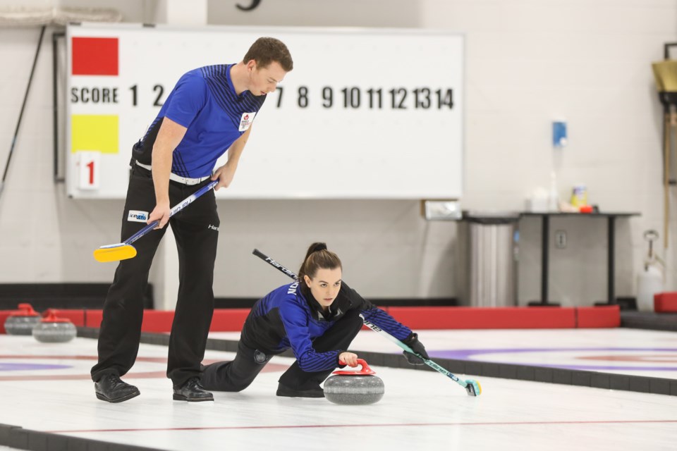 Kyler Kleibrink sweeps Chantele Broderson's rock during finals for the WFG Okotoks Mixed Doubles Classic at the Okotoks Curling Club on Nov. 1. Kleibrink and Broderson won the title by a 7-4 score over Brittany Tran and Aaron Sluchinski. (Brent Calver/Western Wheel)