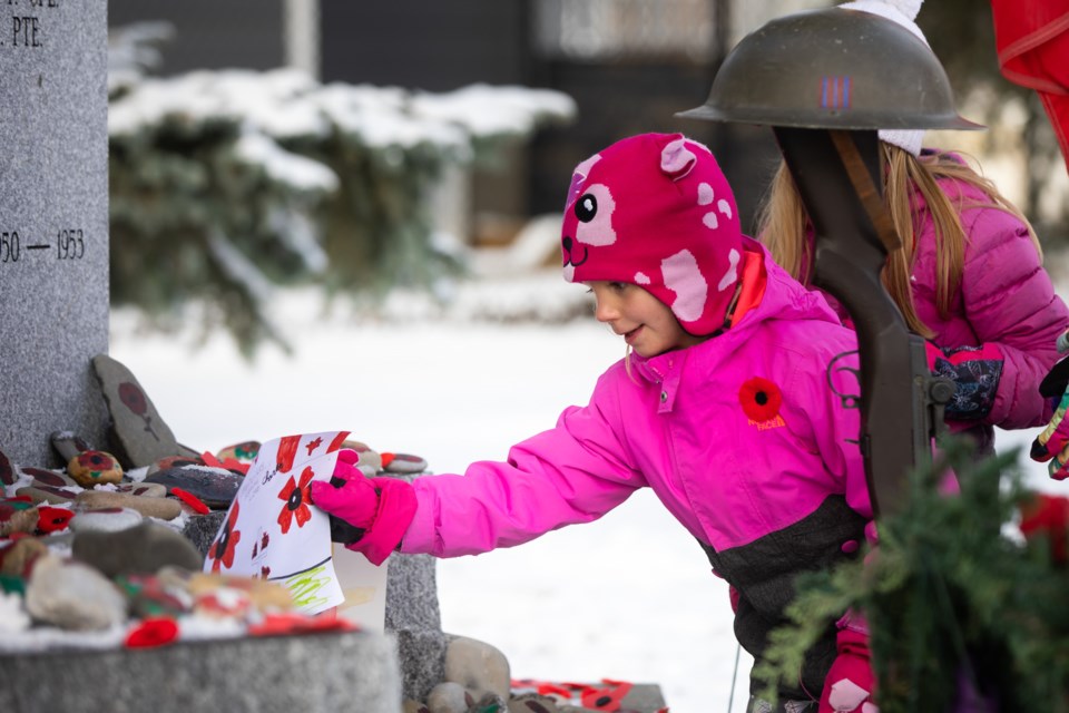 Lennon Mann, 6, places a drawing at the foot of the cenotaph in Okotoks for Remembrance Day on Nov. 11. (Brent Calver/Western Wheel)