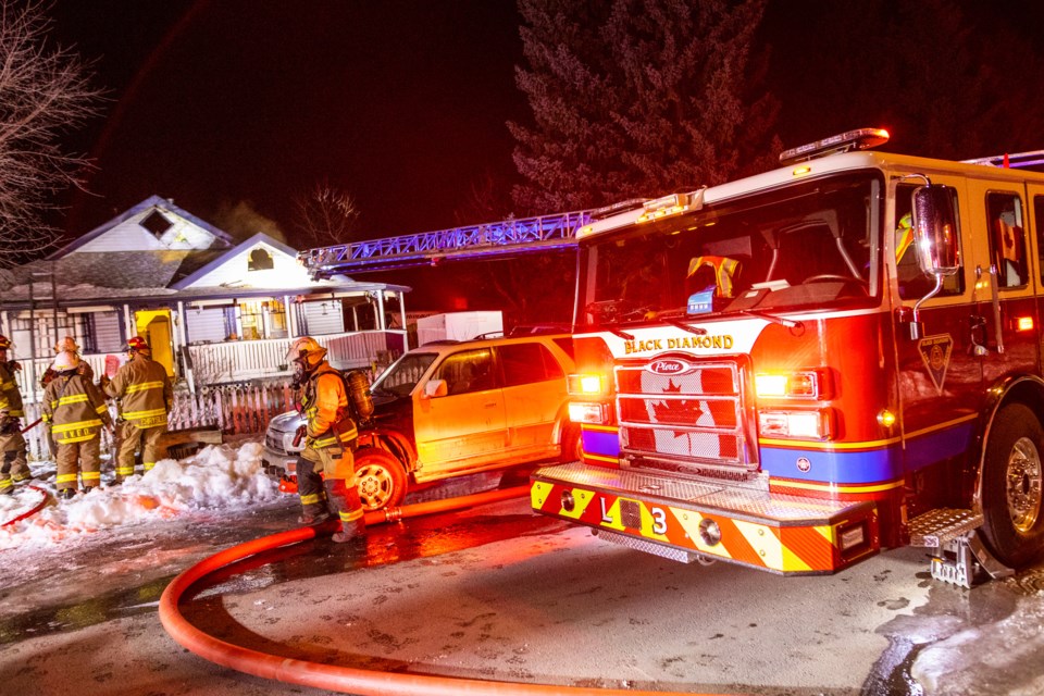 Fire crews from Turner Valley and Black Diamond work to extinguish a fire in a home in Turner Valley on the evening of Jan. 17. The residents were able to get out safely and due to the quick work of fire crews, the fire originating in an upstairs bedroom was extinguished.   |  Brent Calver/Western Wheel