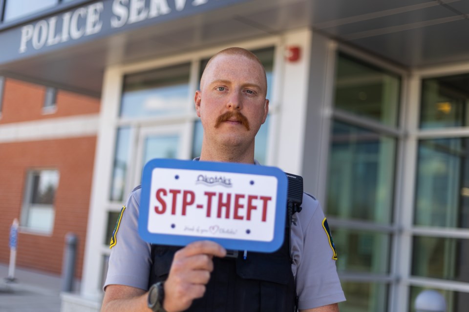 Okotoks peace officer Devon Bartek shows a pamphlet the Town will be distributing to the public, accompanied by theft-resistant licence plate screws to curb plate theft.