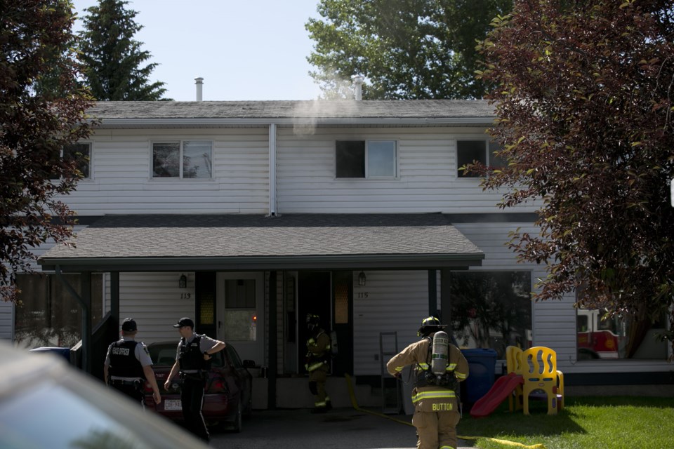 Okotoks firefighters and community peace officers at the scene of a home fire at 115 Elm Place in Okotoks on July 13. There were no injuries. (Bruce Campbell, Western Wheel).