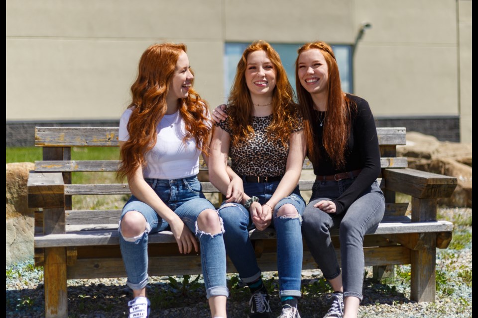 Holy Trinity Academy
class of 2020 graduates
triplets Alexa, Sierra and
Tyra Milliken-Smith share
a laugh at the Okotoks
school on June 4.
(Photo by Devon Langille)