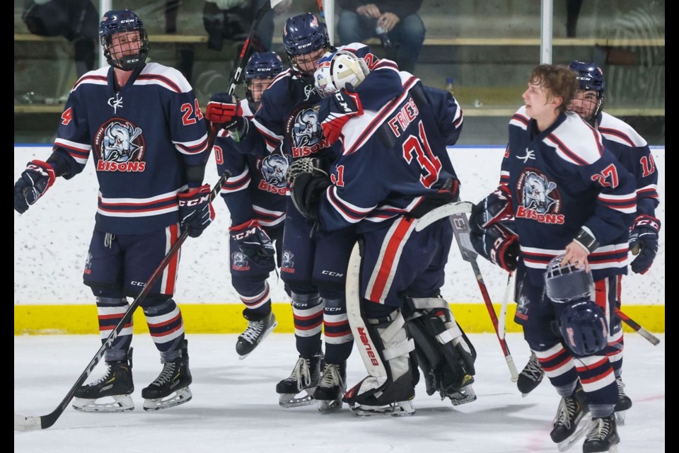 The Okotoks Bisons celebrate Jaevon Buschlen’s overtime winner in the 3-2 victory over the Cochrane Generals in Game 2 of the Heritage Junior Hockey League final on March 19 at the Murray Arena. (Brent Calver/OkotoksTODAY)