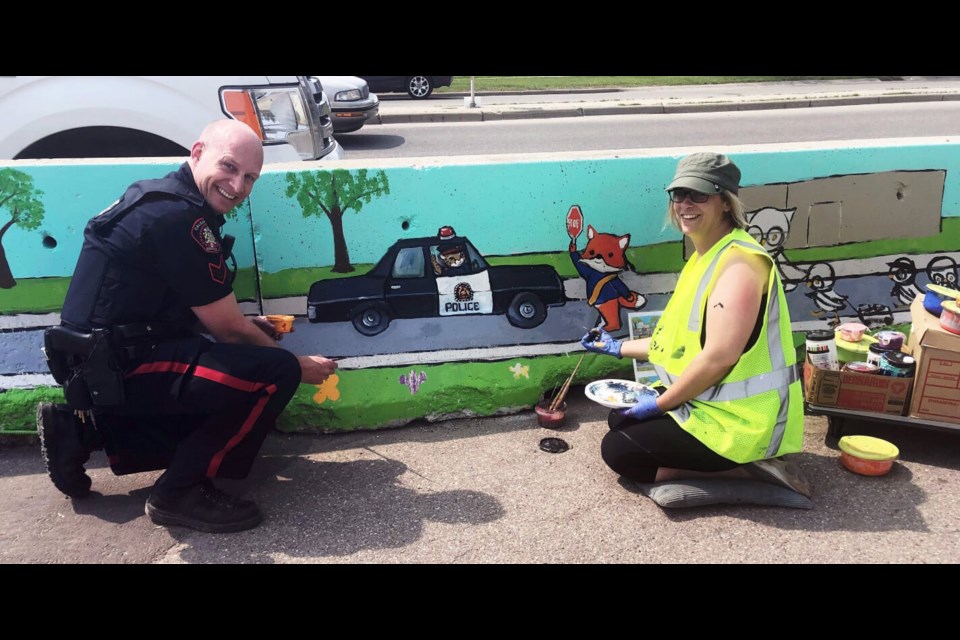 Okotoks artist Jennifer Stables and Calgary Police Const. Chris Langham put some finishing touches on the mural at the Abbey Towne bike park on Memorial Drive in Calgary. (Photo Submitted)