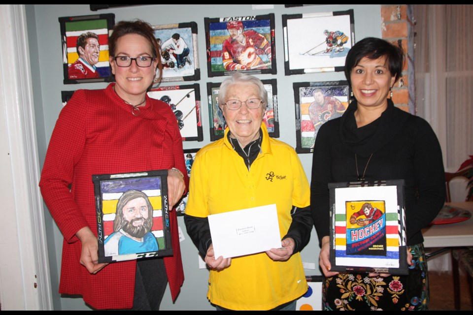 LIneham House Galleries owner Cheryl Taylor, left and Janifer Calvez of Lineham present a $500 cheque to KidSport Okotoks representative Marg Cox in December. The funds came from the sale of a hockey painting done by Timothy Wilson Hoey. 