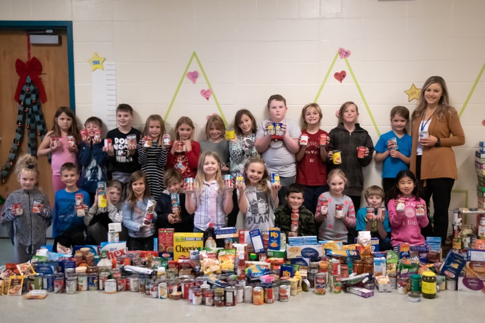 Emily Baranyay and her Grade 3 students proudly hold the food donations they’ve collected for their Giving Trees program at C. Ian McLaren School. (Photo courtesy of Hayley Brough)